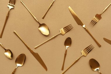 Kahverengi arka planda şık altın çatal bıçak takımı