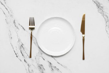 Altın çatallı temiz tabak ve beyaz arka planda bıçak.