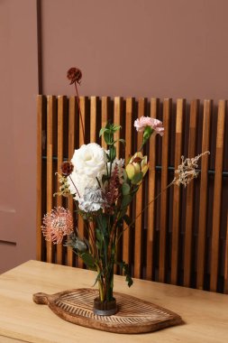 Kenzan, kahverengi duvarın yanındaki rafta ikebana var.