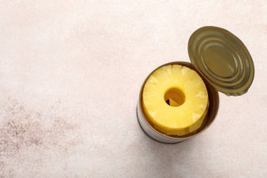 Beyaz arka planda konserve ananas halkaları olan teneke kutu.