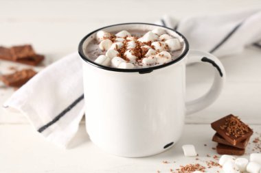 Bir fincan sıcak kakao, marşmelov ve beyaz ahşap arka planda tatlı çikolata.