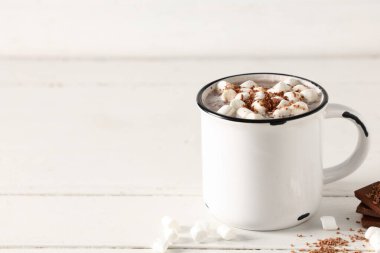 Beyaz ahşap arka planda kremalı bir fincan sıcak kakao.