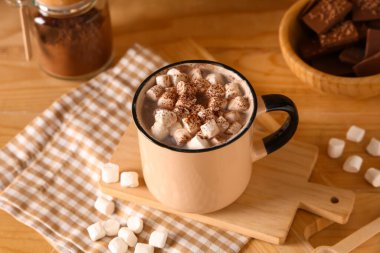 Bir fincan sıcak kakao, marşmelov ve ahşap arka planda tatlı çikolata.