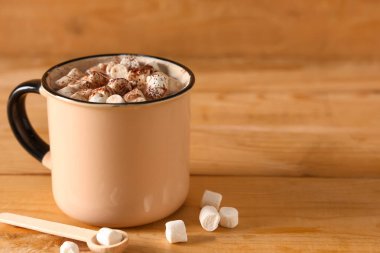 Bir fincan sıcak kakao, marşmelov ve ahşap arka planda.