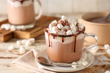 Krem şantili ve beyaz ahşap masada marşmelovlu bir bardak sıcak kakao.