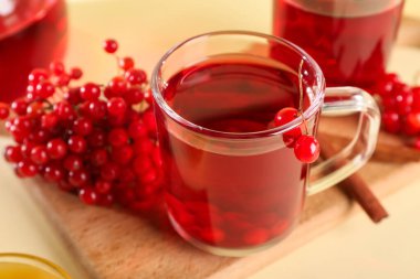 Sarı arka planda tarçınlı ve meyveli bir bardak sıcak viburnum çayı, yakın plan.