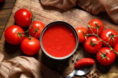 Biberli konserve domates ezmesi ve ahşap arka planda sebzeler.