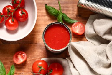 Ahşap arka planda fesleğen yapraklı ve sebzeli teneke kutu domates ezmesi.