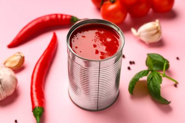 Teneke kutu lezzetli domates ezmesi ve pembe arka planda farklı malzemeler, yakın plan.