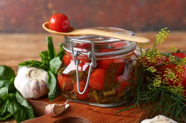 Lezzetli konserve domates kavanozu ve ahşap masada farklı baharatlar.