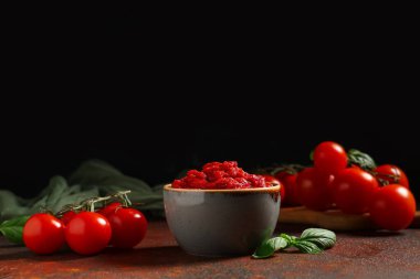 Bir kase lezzetli domates ezmesi, fesleğen yaprakları ve sebzeler.