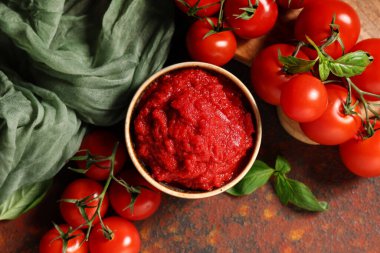 Koyu arkaplanda fesleğen yapraklı ve sebzeli bir kase lezzetli domates ezmesi.