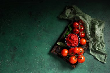 Yeşil arka planda fesleğen yapraklı ve sebzeli bir kase lezzetli domates ezmesi.