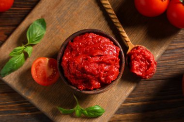 Tahta arka planda fesleğen yapraklı bir kase dolusu lezzetli domates ezmesi.