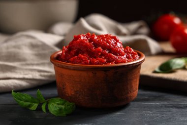 Siyah ahşap masa üzerinde fesleğen yapraklı bir kase lezzetli domates ezmesi.