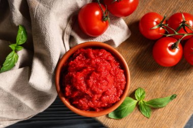 Siyah ahşap arka planda fesleğen yapraklı ve sebzeli bir kase lezzetli domates ezmesi.