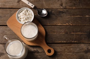 Bir bardak taze kefir ve ahşap arka planda süzme peynirli kase.