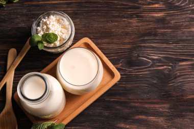 Bir bardak taze kefir ve ahşap arka planda naneli süzme peynir.