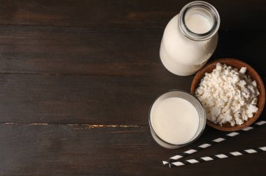 Bir şişe taze kefir ve ahşap arka planda süzme peynirli kase.