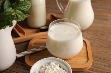 Bir bardak taze kefir naneli ve ahşap arka planda bir kase süzme peynir, yakın plan.