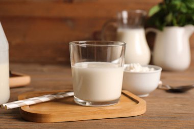 Bir bardak taze kefir ve ahşap arka planda süzme peynirli kase.