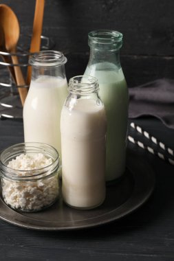 Siyah ahşap arka planda süzme peynirli taze kefir ve kavanozlar.