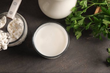 Bir bardak taze kefir maydanozlu ve siyah arka planda süzme peynirli.