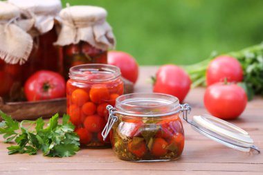 Dışarıdaki ahşap masada maydanozlu konserve domates kavanozları.