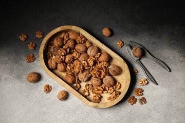 Ahşap tepside lezzetli cevizler ve fındıkkıran ve gri grunge arka planda