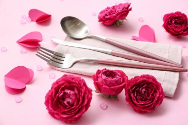 Çatal bıçak takımı, peçete, gül çiçeği ve pembe arkaplanlı boncuklar, yakın plan. Sevgililer Günü kutlaması