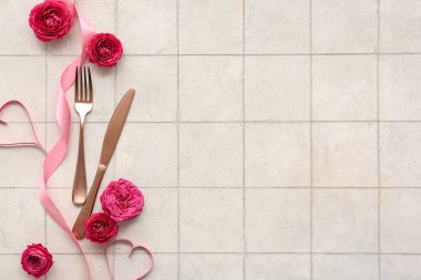 Çatal bıçaklı kompozisyon, gül çiçekleri, kurdele ve bej kaplamalı kağıt kalpler. Sevgililer Günü kutlaması