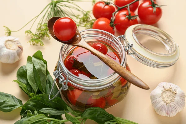 Bej arka planda sarımsaklı, dereotlu ve fesleğenli konserve domates kavanozu. Yakın plan.