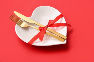 Kırmızı arka planda kurdeleli Sevgililer Günü için masa ayarları, yakın plan