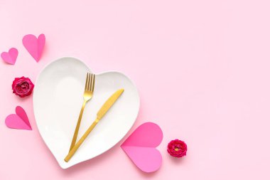 Sevgililer Günü için güzel bir masa, pembe arka planda güller ve kağıt kalplerle.