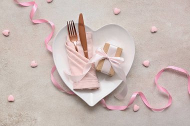 Beyaz grunge arka planda Sevgililer Günü için hediye kutusu, kurdele ve dekoratif kalplerle masa ayarı