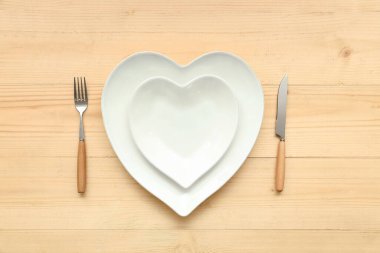 Ahşap zemin üzerinde kalp şeklinde plakalar olan Sevgililer Günü için masa ayarı