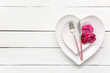 Beyaz ahşap arka planda gül çiçekleri olan Sevgililer Günü için masa ayarı