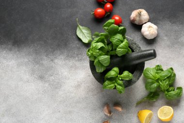 Kabuklu havan, fesleğen yaprağı, limon, domates ve gri grunge arka planda sarımsak.