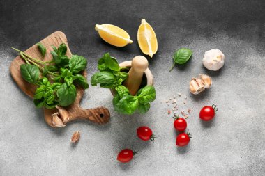 Fesleğen yapraklı ahşap havan, domates, sarımsak ve limon.