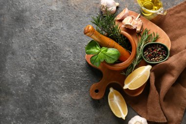 Fesleğen yapraklı ahşap havan, biberiye ve koyu arkaplanda malzemeler.