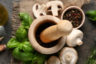 Karabiberli ahşap havan topu, fesleğen yaprağı ve koyu arkaplanda taze mantar.