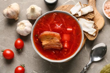 Bir kase geleneksel Ukrayna çorbası, farklı malzemeler ve arkaplanda lezzetli domuz yağıyla dilimler.