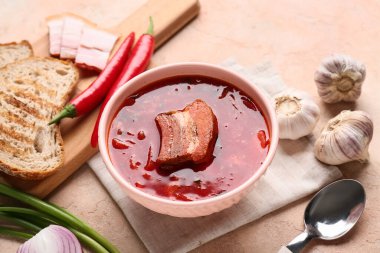 Bir kase geleneksel Ukrayna çorbası ve bej arka planda farklı malzemeler, yakın plan.