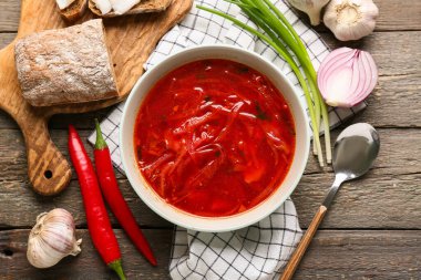 Bir kase geleneksel Ukrayna çorbası ve ahşap arka planda farklı malzemeler.