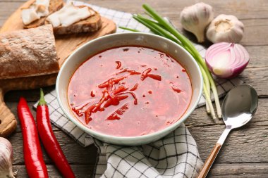 Bir kase geleneksel Ukrayna çorbası, farklı malzemeler ve ahşap arka planda lezzetli domuz yağıyla dilimler, yakın plan.