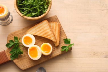 Kaynamış yumurta, maydanoz ve beyaz ahşap arka planda dilimlenmiş ekmek dilimleri.