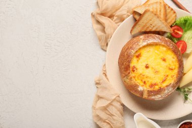 Ekmek kabında peynir çorbası, marul, tost, mikro yeşil ve açık arkaplanda domates.