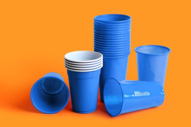 Turuncu arkaplanda mavi plastik bardaklar