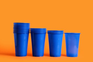 Turuncu arkaplanda mavi plastik bardaklar