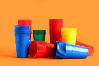 Turuncu arka planda birçok renkli plastik bardak